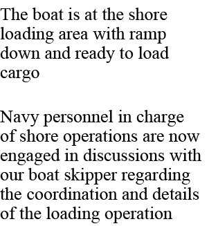 The boat is at the shore loading area with ramp down and ready to load cargo Navy personnel in charge of shore operat...